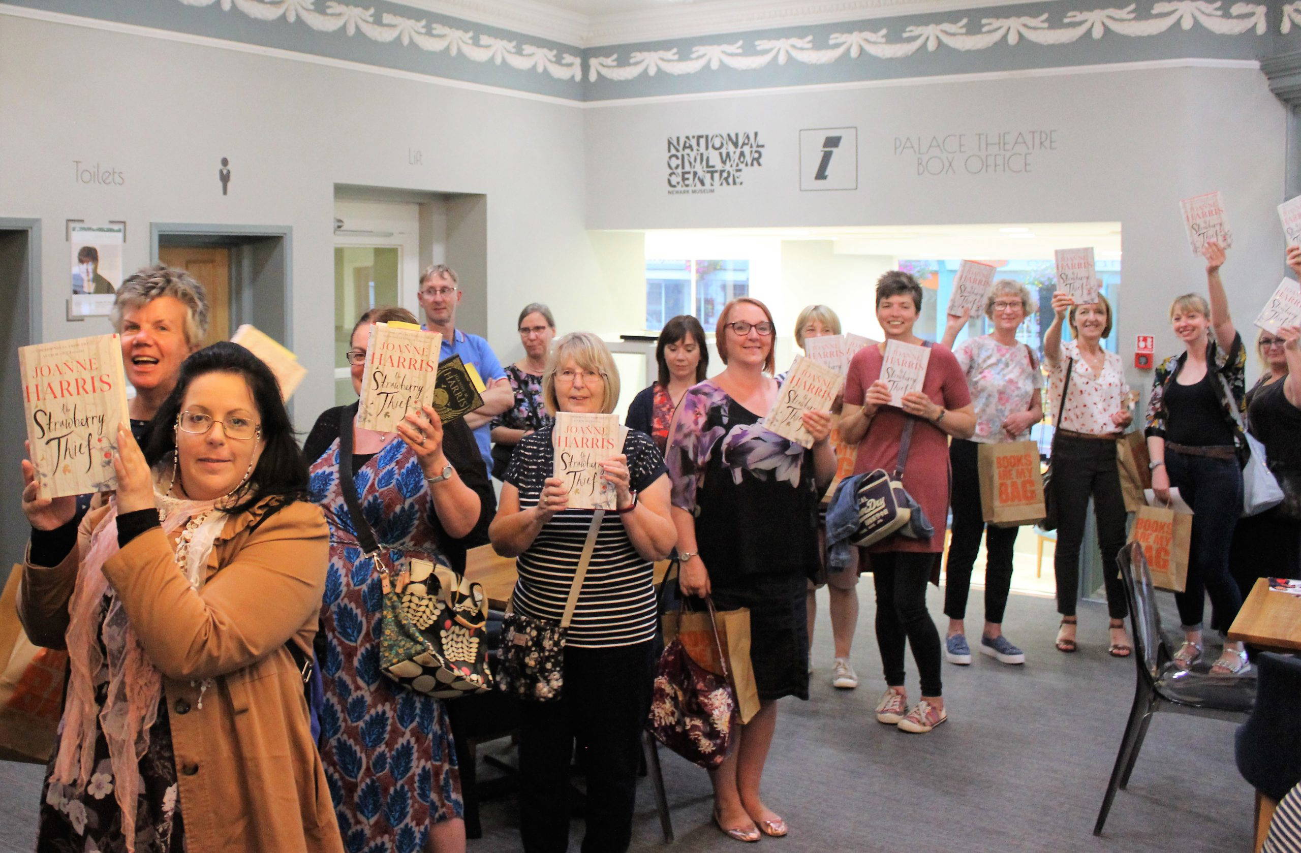 People in the queue for a book signing at the Palace Theatre in Newark. They are all holding up a copy of The Strawberry Thief by Joanne Harris.